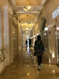 زنی درحال عبور از راه‌روی مرکز خرید مدرن الهیه