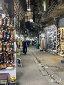مردی درحال نگاه کردن به ویترین مغازه کفش‌فروشی بازار سید ولی