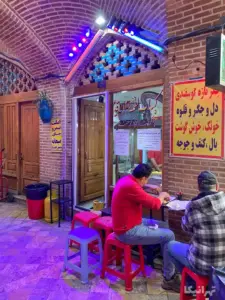 دونفر درحال خوردن غذا در جلوی رستورانی در بازارچه عودلاجان