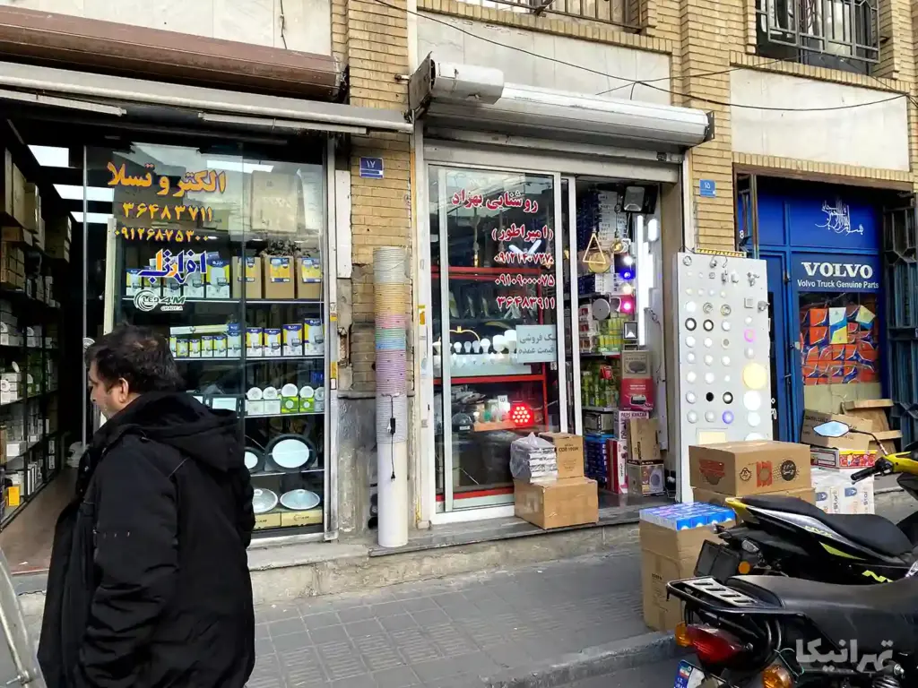 مردی جلوی مغازه‌های الکتریکی ایستاده