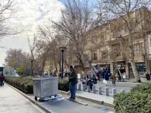 مردم در حال تردد در خیابان ناصرخسرو و مردی که کنار پیاده‌رو ایستاده