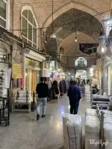چند مرد در حال عبور و چند مرد نشسته در دالان دوم ملک بازار