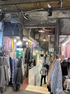 دو فروشنده در مغازه‌های خود در دو نبش ورودی دالان سوم ملک بازار