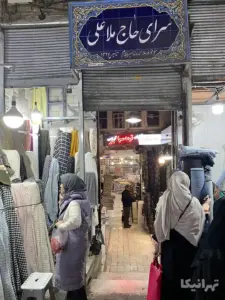 چند نفر در حال انتخاب پارچه در جلوی ورودی سرای حاج ملاعلی بازار