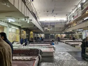 چند نفر در حال دیدن فرش‌های دستباف در سرای روحانی‌نوی بازار