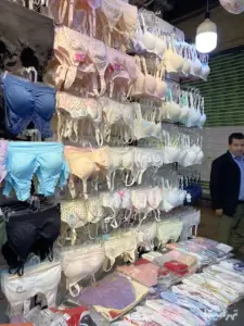 مردی از مقابل لباس‌های زیر چیده شده در سرای روحیه بازار می‌گذرد