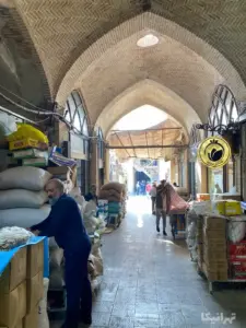 فروشندگان ایستاده جلوی فروشگاه خود در دالان ورودی سرای سلیمان‌خان بازار