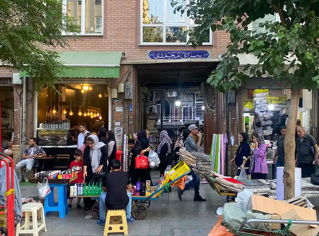 مردم در حال عبور، خرید و فروش در پیاده‌وری بازار ۱۵ خرداد جلوی درب ورودی سرای محمدی