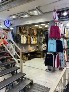 فروشنده در مغازه پوشاک خود ایستاده است