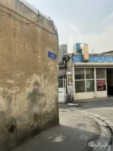 مغازه صنایع فلزی پشت دیوار و تابلوی کوچه صادقی