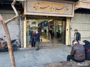 چند نفر در خیابان ناصرخسرو در مقابل داساژ آینه نشسته یا ایستاده‌اند