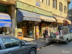 مردی در حال عبور از جلوی پاساژ احمدی بازار و مردی در پشت پانت مشغپل جابه‌جایی بار