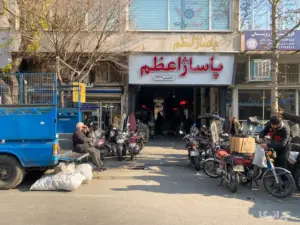 چند نفر جلوی پاساژ اعظم چراغ برق ایستاده‌اند