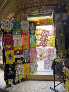 لباس‌های چیده شده در جلو و داخل یک فروشگاه در پاساژ المهدی ۳ بازار