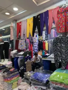 مردی در مغازه خود در میان لباس‌ها نشسته با تلفن مکالمه می‌کند