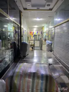 لباس‌های چیده شده در انتها و بسته‌های چیده شده در کناره‌ها در پاساژ تهران کوچه ارامنه بازار