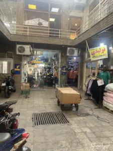 لباس‌های چیده شده و موتورهای پارک شده در داخل حیاط پاساژ جعفری ۱۵ خرداد