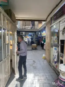مردی در دالان ورودی پاساژ جعفری ۱۵ خرداد ایستاده است