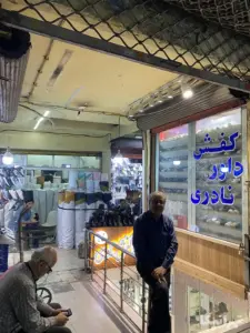 دو مرد در ورودی پاساژ حسن‌خانی بازار نشسته‌اند
