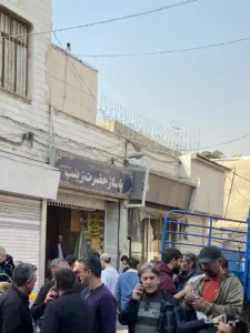 مردم در کوچه احمدی بازار ایستاده‌اند در مقابل پاساژ حضرت زینب (س) بازار