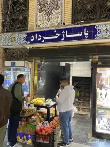 مردی در حال خرید از دستفروشی در جلوی ورودی بازار بزازهای پاساژ خرداد