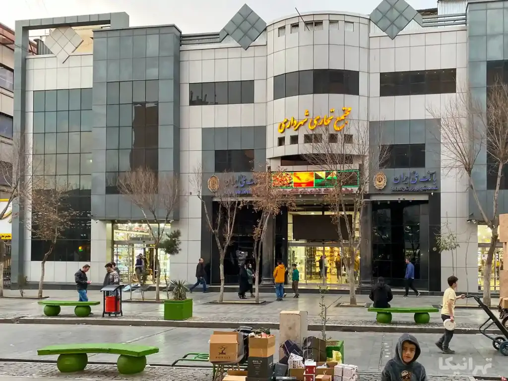 چند نفر جلوی ورودی پاساژ شهرداری شوش ایستاده‌اند