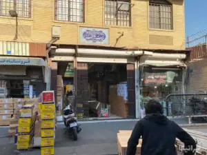 مردی در حال جابه‌جایی چرخ باربری در کوچه احمدی بازار مقابل پاساژ فجر