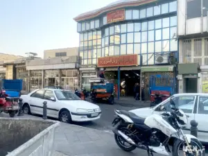 چند مرد جلوی پاساژ فیروزه محمدیه ایستاده به مردانی در حال جابه‌جایی بار است نگاه می‌کنند