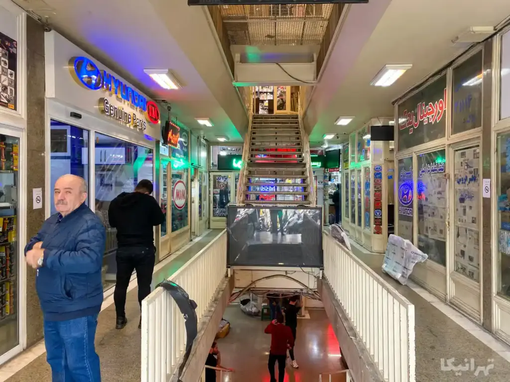 مردی در پاساژ ولیعصر خیابان ملت ایستاده به دوربین نگاه می‌کند
