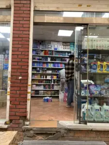 مردی درحال چیدن قفسه‌های مغازه مواد شوینده خارجی در کوچه معظم‌الدوله بازار تهران
