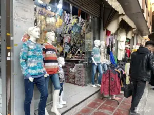 مردی از جلوی یک مغازه پوشاک بچگانه در کوچه مهدوی بازار گذر می‌کند